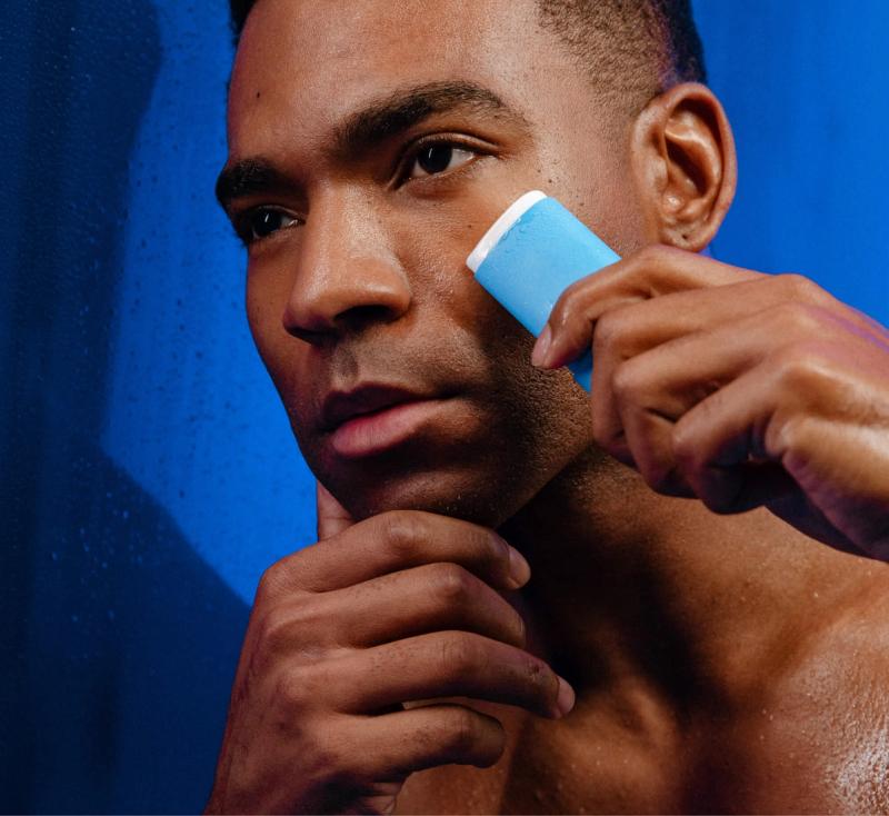 a man is shaving his face with a blue stick .