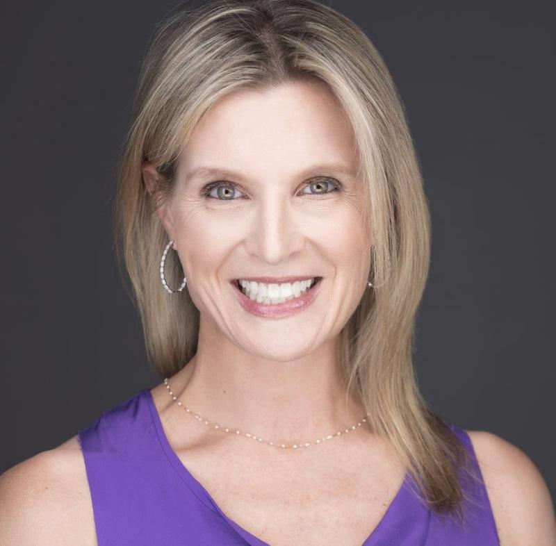 a woman wearing a purple tank top and earrings is smiling for the camera .