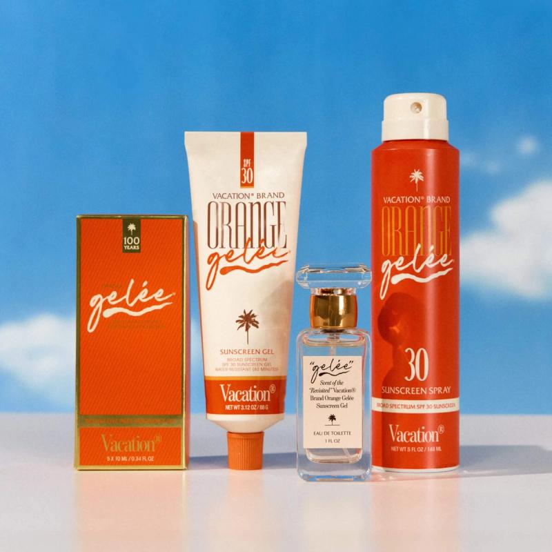A collection of Vacation Brand Orange Gelée sunscreens and fragrance products against a blue sky.