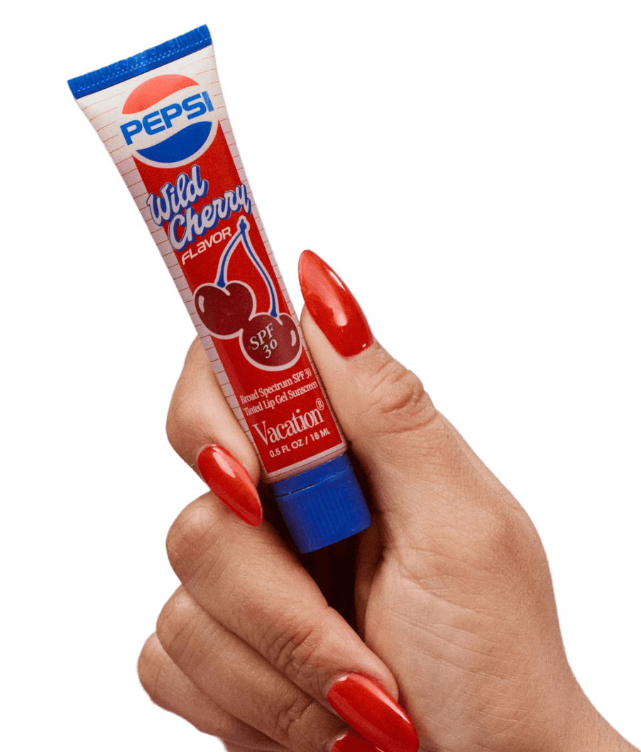 A hand with long red nails holds a tube of Pepsi Wild Cherry Flavor SPF 30 lip balm by Vacation