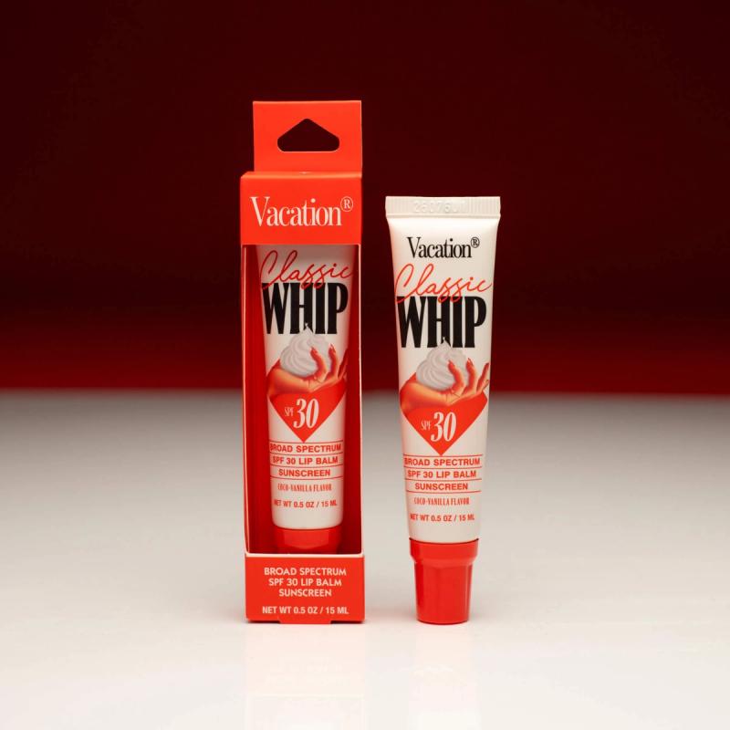 Two tubes of Vacation Classic Whip SPF 30 Lip Balm Sunscreen, one inside a red box and the other standing beside it, against a red background.