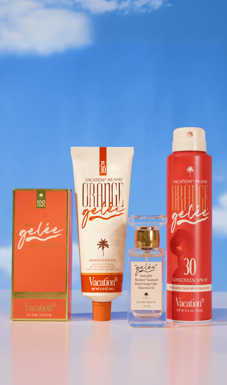 Four Vacation Brand "Orange Gelée" products, including SPF 30 sunscreens, a perfume bottle, and a box, on a reflective surface under a blue sky.