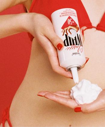 a woman in a red bikini is holding a can of whip cream