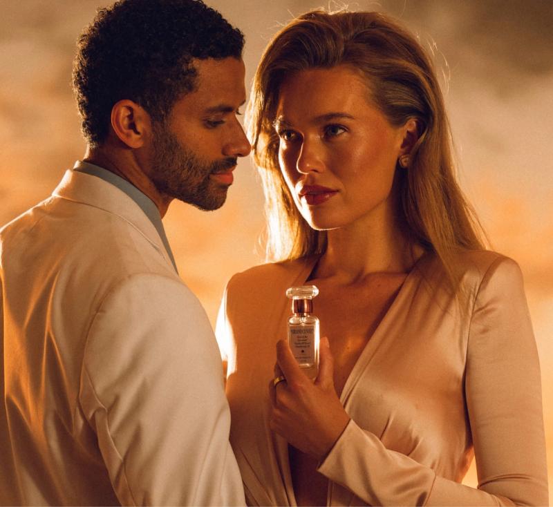 a blonde woman and dark haired man pose with "GRAND CUVÉE" in the sunset