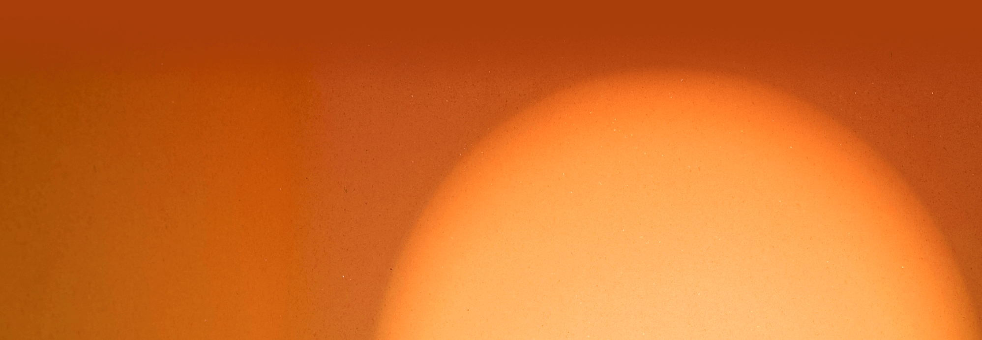 a close up of an orange background with a sun in the middle .