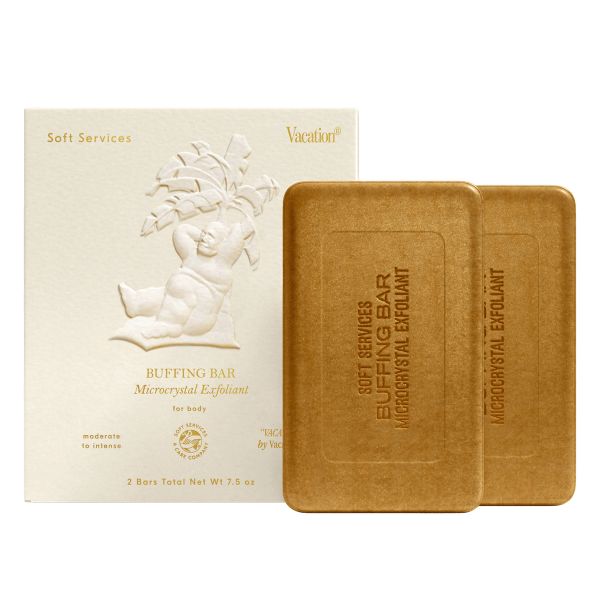 A white box for Soft Services Buffing Bar Microcrystal Exfoliant with an embossed cherub design, next to two rectangular brown exfoliant bars.