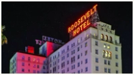 The Roosevelt Hotel at night, with a prominent neon sign on its roof.