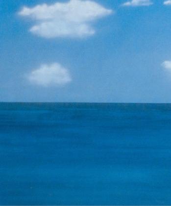 a blue ocean with white clouds in the sky