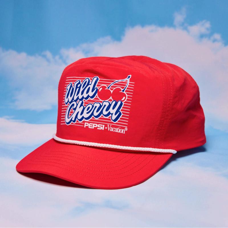 A red hat with a "Wild Cherry PEPSI-Vacation" logo and cherry graphic on the front, set against a blue sky with clouds.