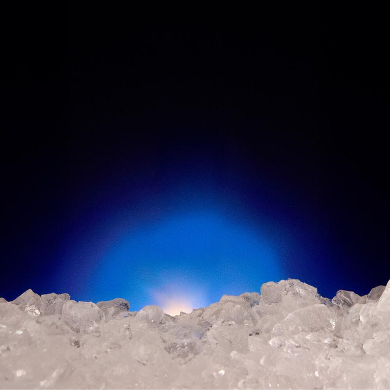 Crushed ice in the foreground with a blue and white light glowing from behind.