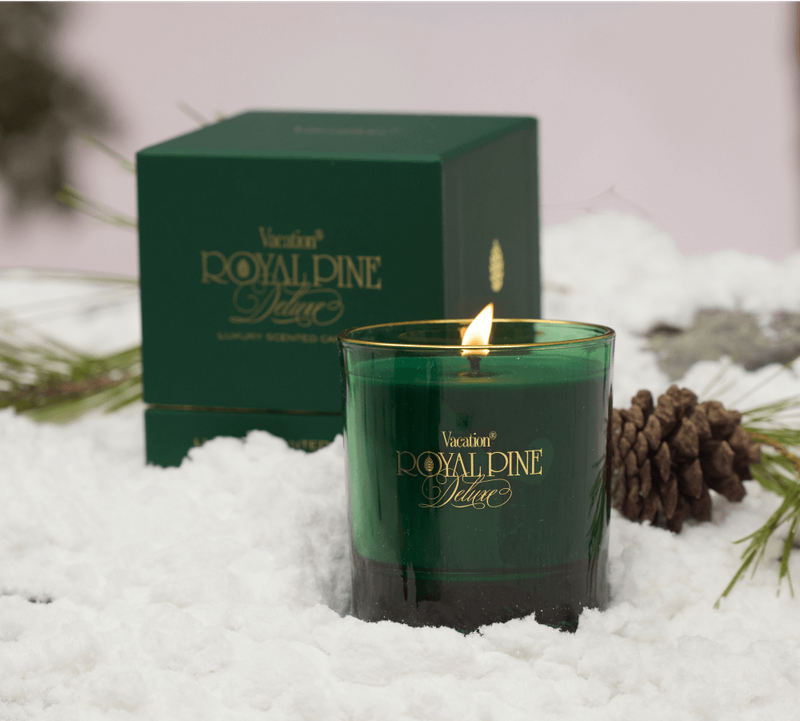 a Royal Pine Deluxe candle and gift box in snow with pinecones and pine needles