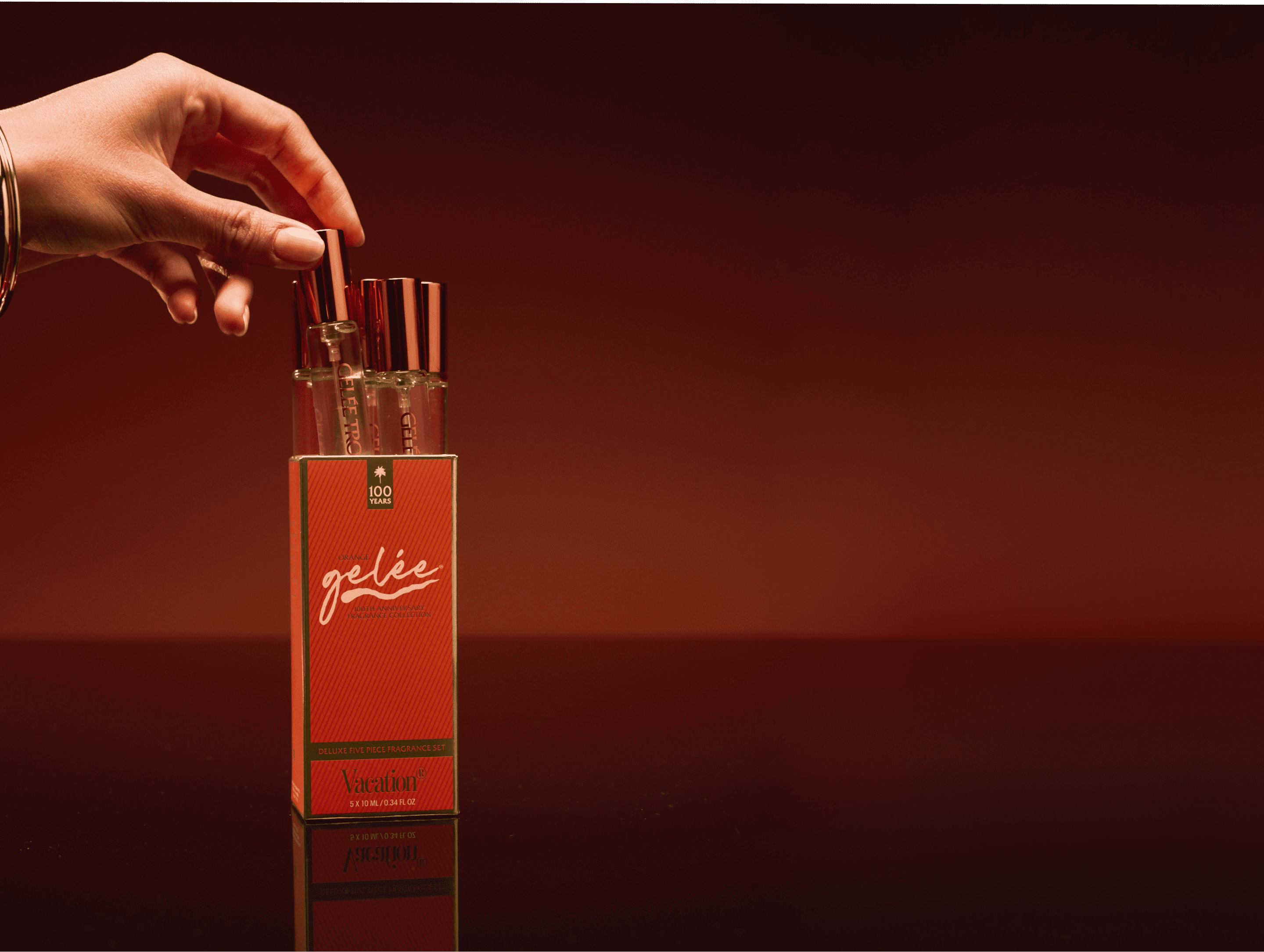 A hand pulling a mini perfume bottle from a "gelée Vacation" fragrance set.