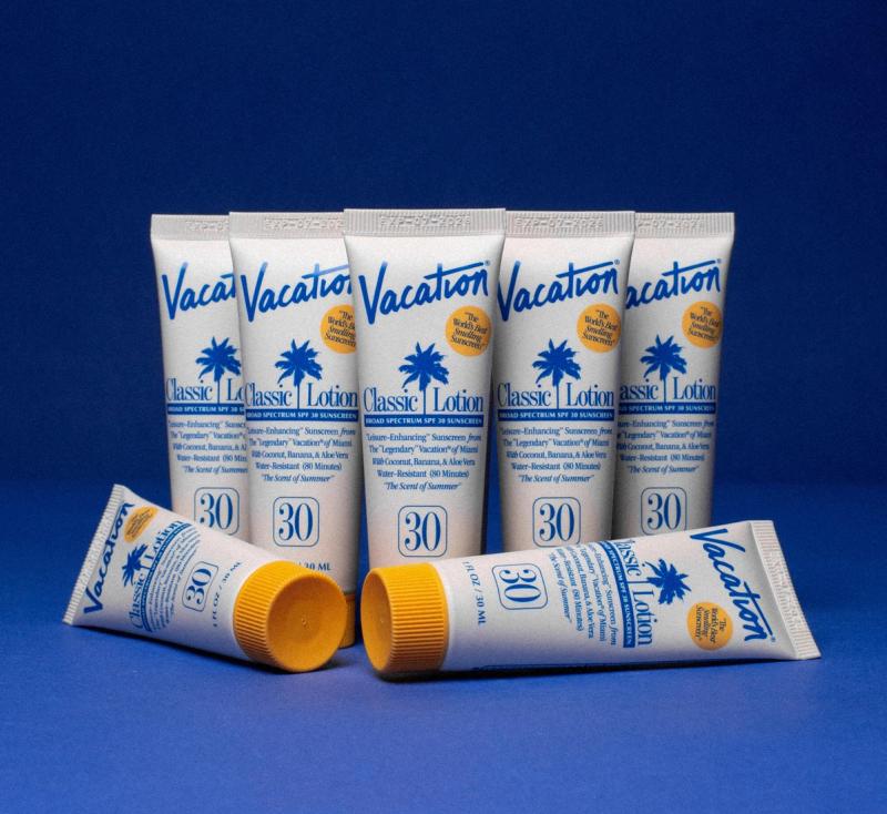 a group of tubes of vacation lotion are stacked on top of each other on a blue surface .