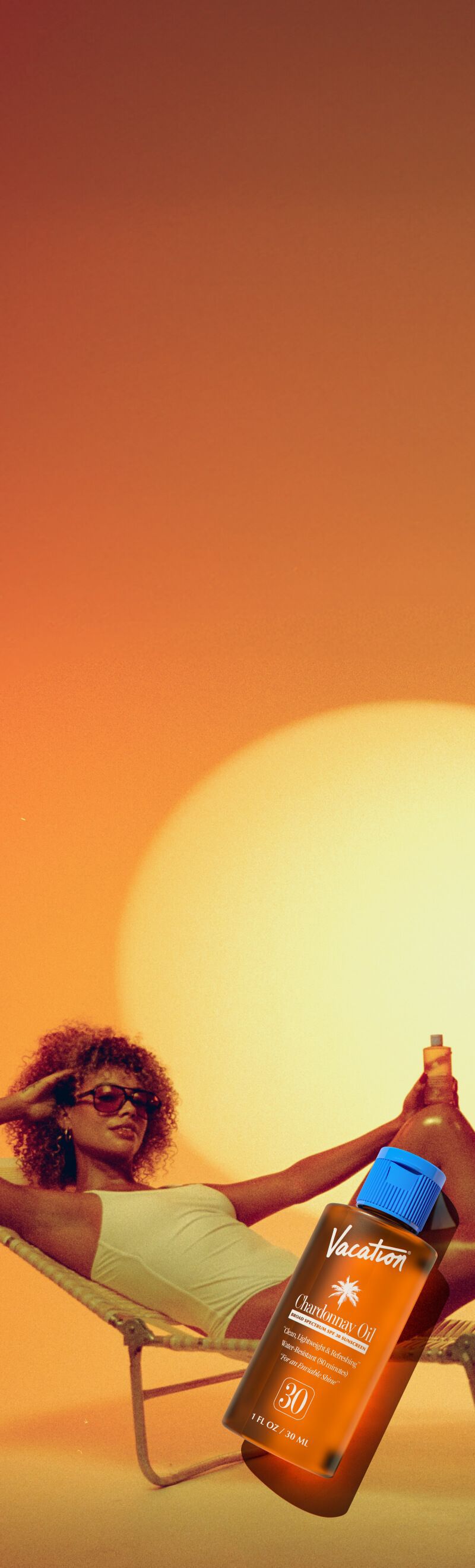 A woman in a white swimsuit lounges on a chair in the sunset