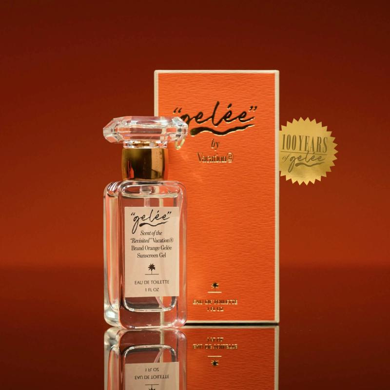 A clear bottle of "gelée" by Vacation Eau de Toilette with an orange gelée sunscreen scent, next to its orange box featuring a "100 YEARS" sticker.