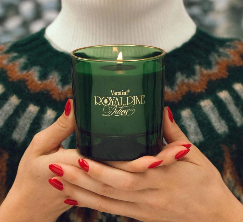 a close up of a woman's hands with red fingernails holding a Royal Pine Deluxe candle