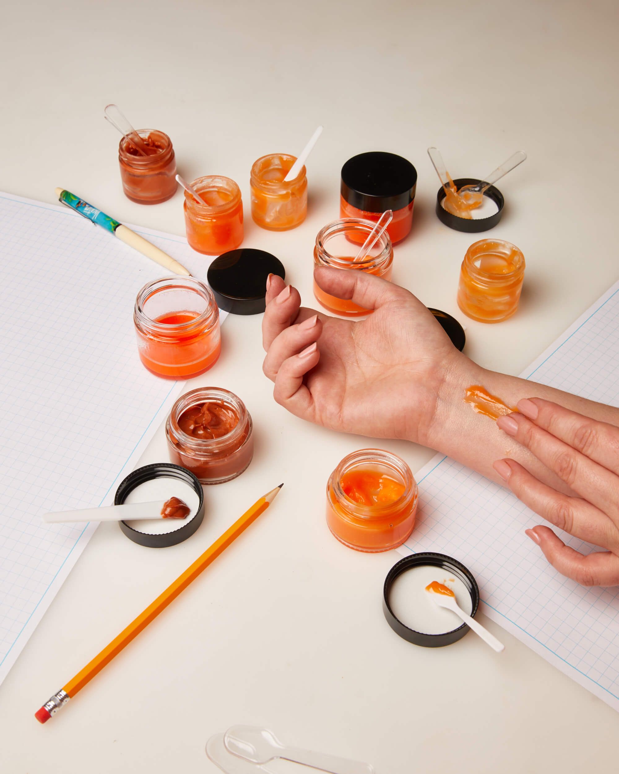 a person is applying a small jar of orange gel to their wrist