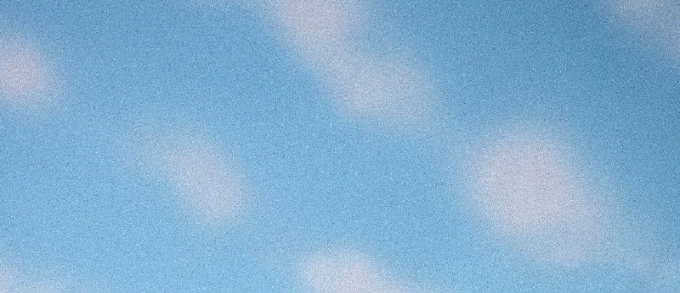 Light blue sky with scattered white clouds