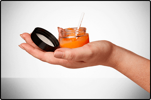 a hand is holding a jar with a spoon in it