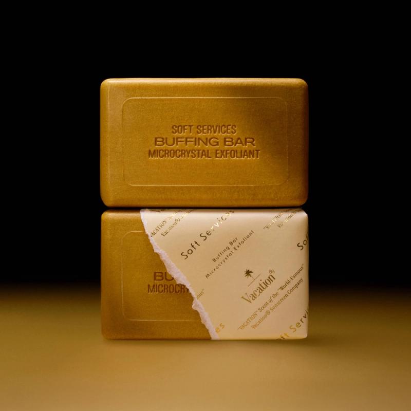 Two stacked golden bars of Soft Services Buffing Bar Microcrystal Exfoliant, one unwrapped and one partially wrapped with "Vacation" scent branding.