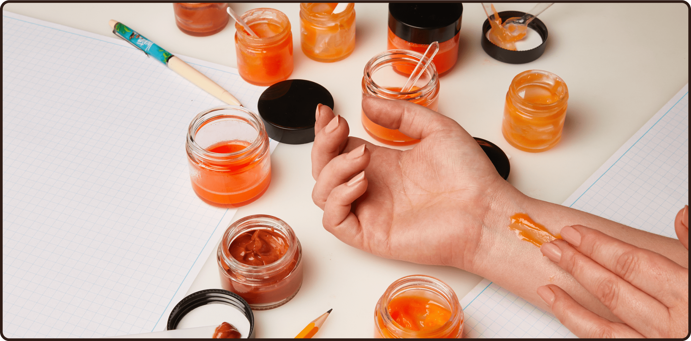 a woman applying a jar of orange liquid to her wrist