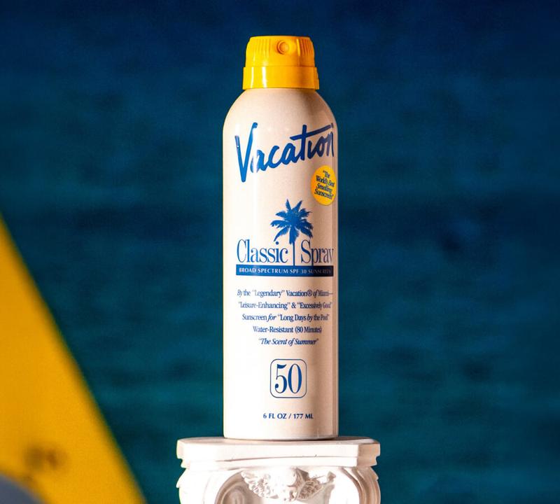 A white spray can of Vacation Classic Spray SPF 30 sunscreen with a yellow cap.