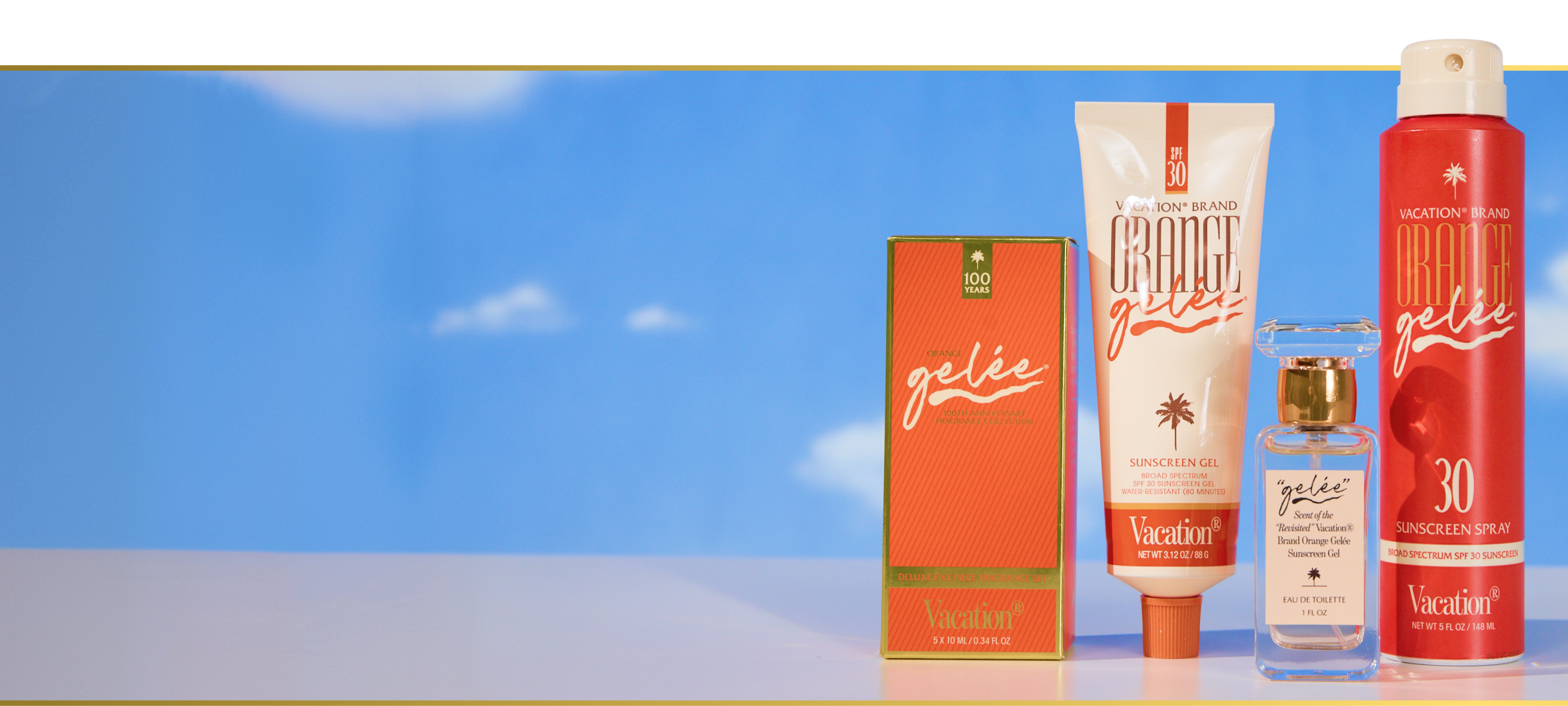 Vacation Brand "Orange Gelée" sunscreen gel, spray, perfume, and box against a blue sky.