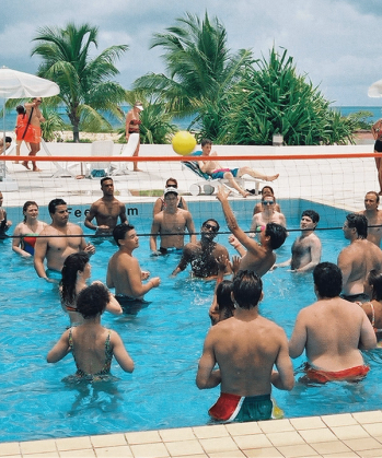 a group of people are playing volleyball in a pool with a net that says esm