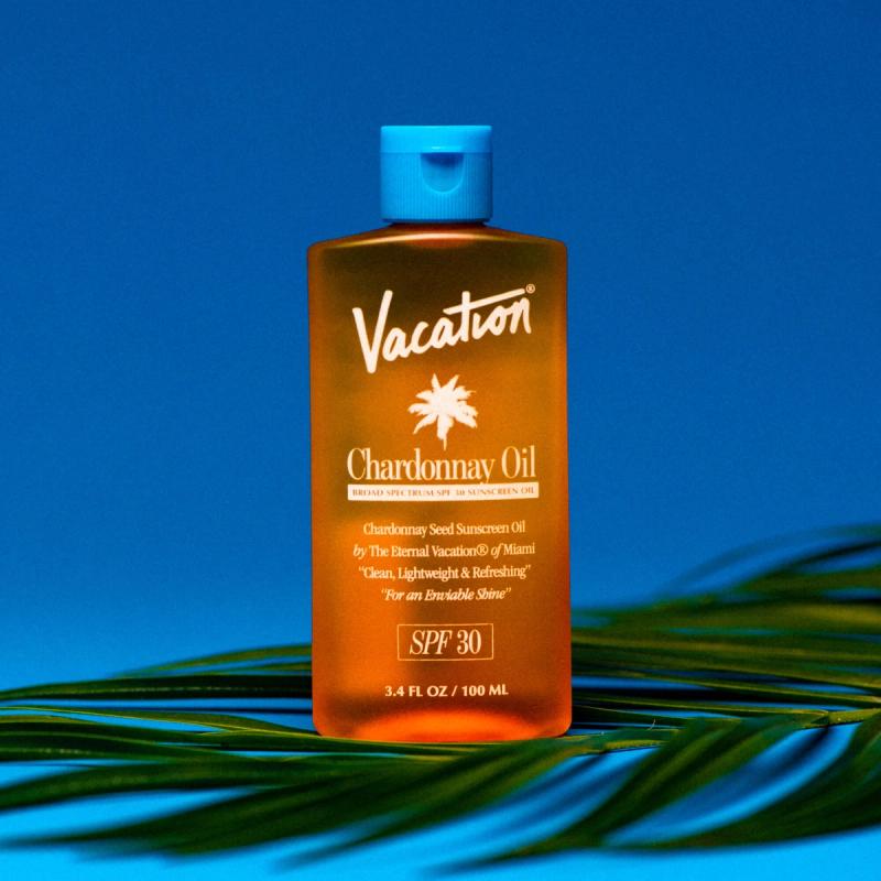 a bottle of vacation chardonnay oil is sitting on top of a palm tree leaf .