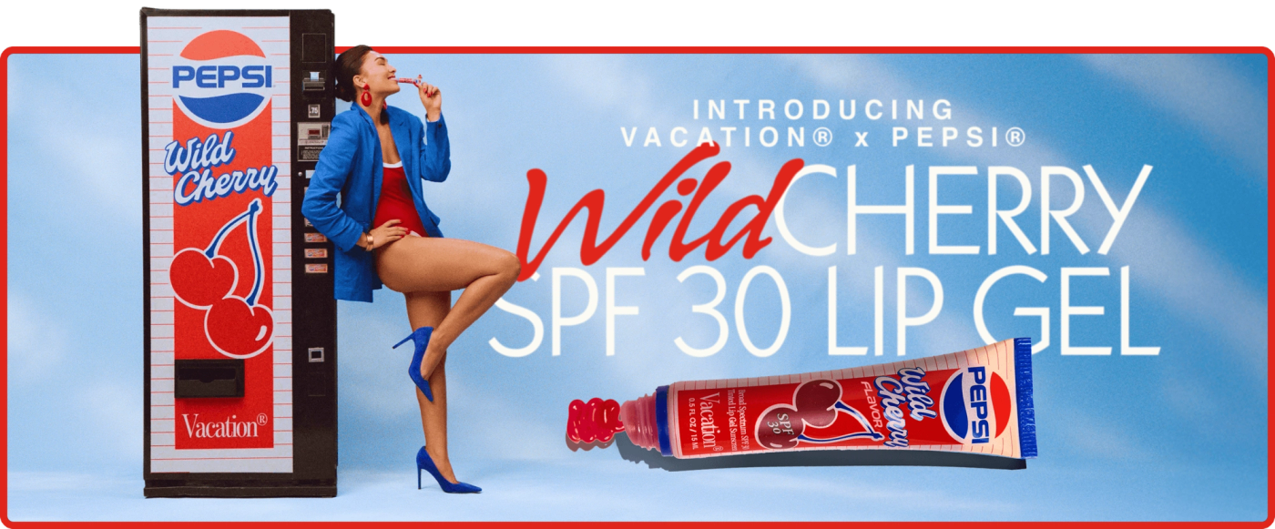 A woman poses with a Pepsi Wild Cherry vending machine and a tube of Vacation x Pepsi Wild Cherry SPF 30 Lip Gel.