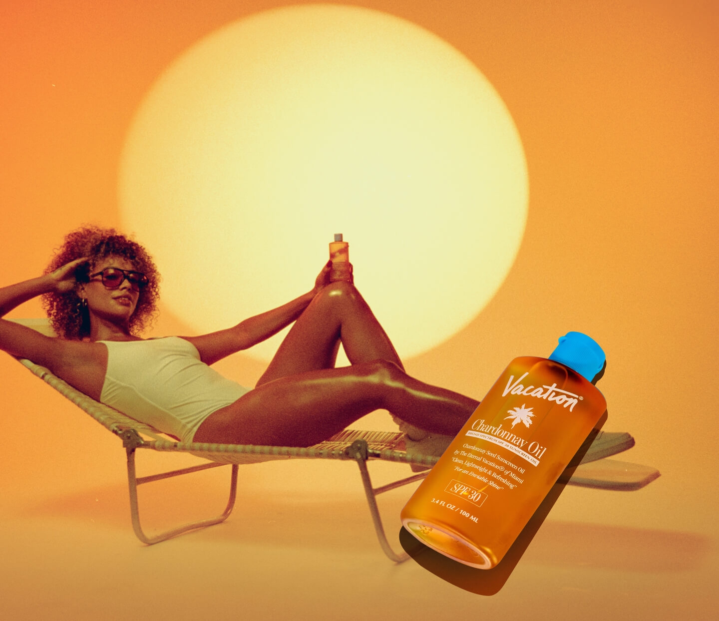 A woman in a white swimsuit lounges on a chair in the sunset