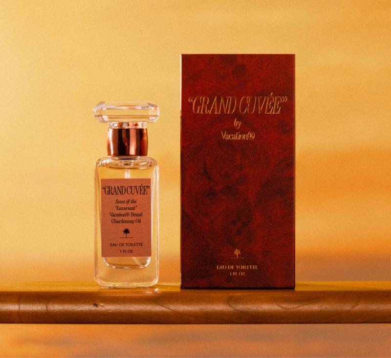 a bottle of "GRAND CUVÉE" sits on the rail of a ship at sunset