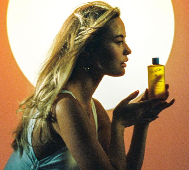 a woman in a blue bikini is spraying sunscreen on her body .