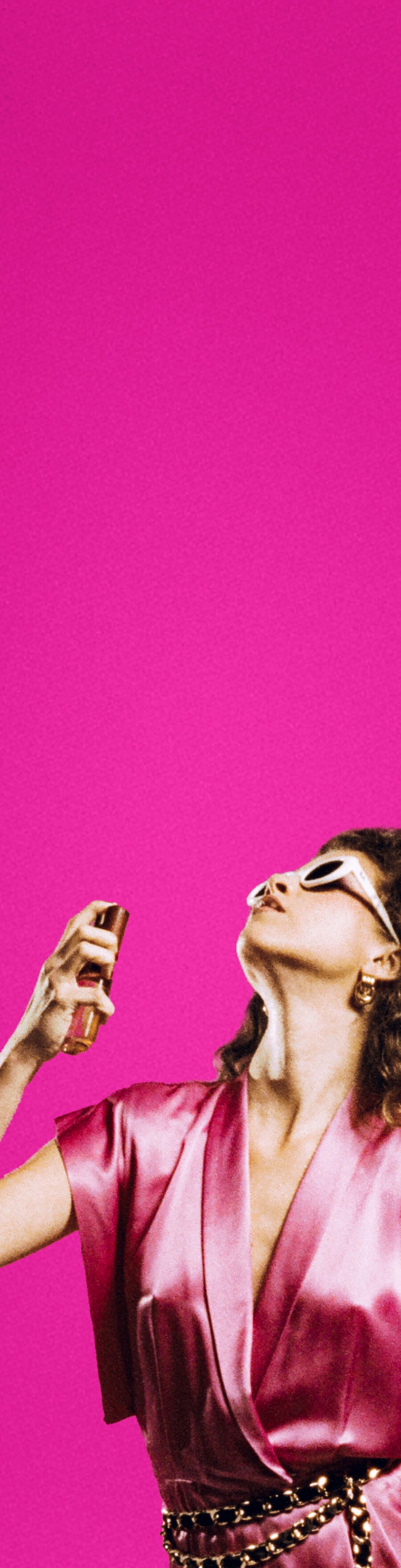 a woman in a silk pink jumper is spraying body mist