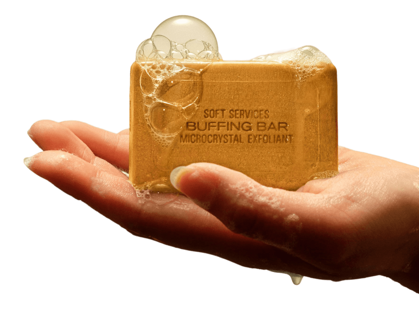 A hand holds a sudsy bar of Soft Services Buffing Bar Microcrystal Exfoliant.