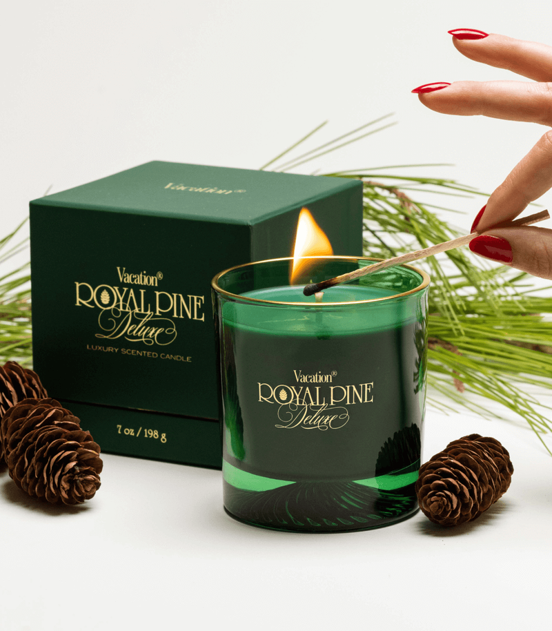 a vacation royal pine deluxe candle is lit with a match