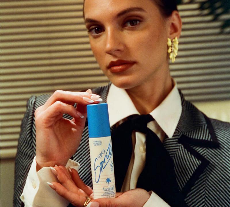 a woman in a suit and tie is holding a bottle of deodorant .
