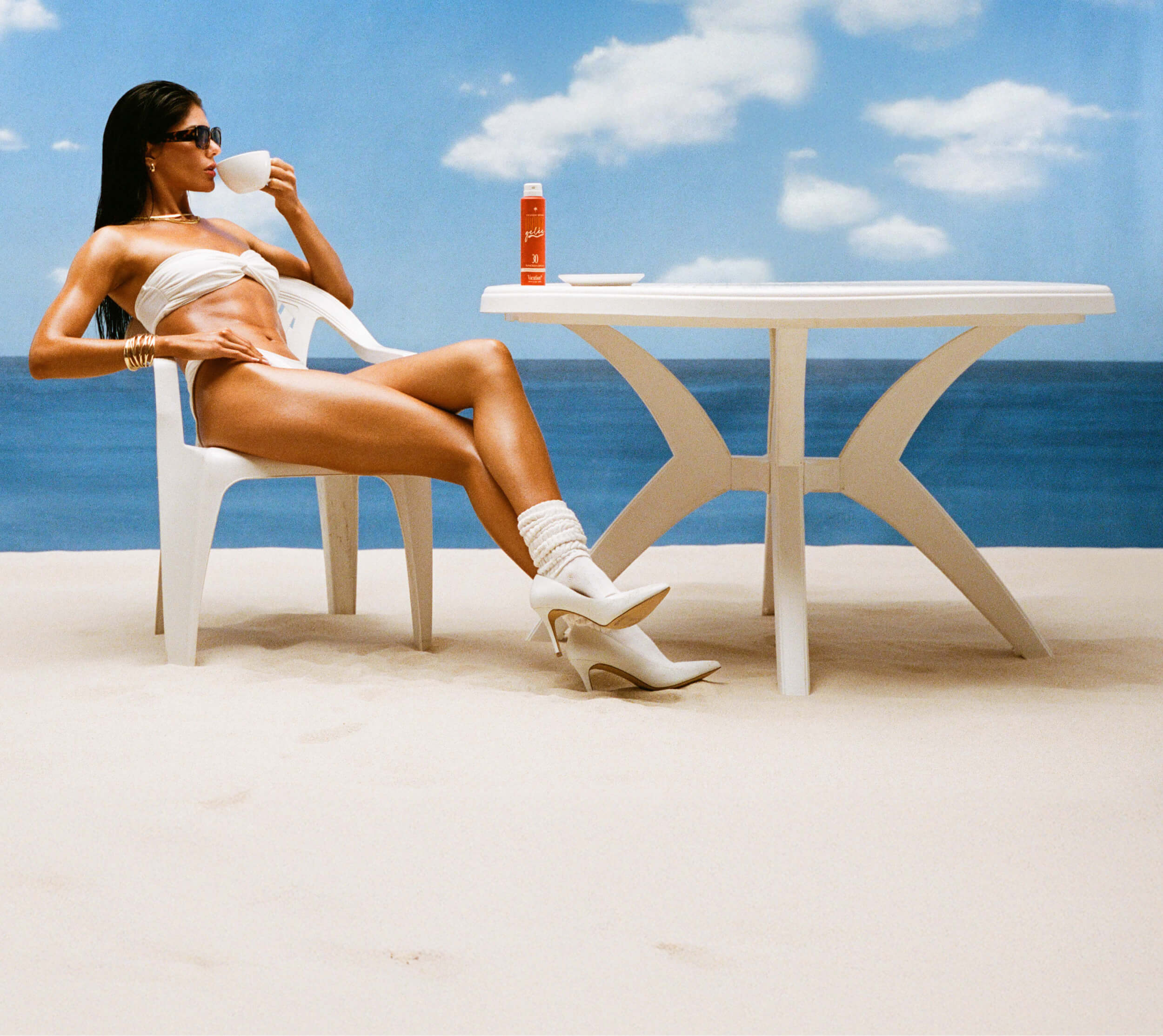 a woman sipping a cappuccino at a café table on the beach