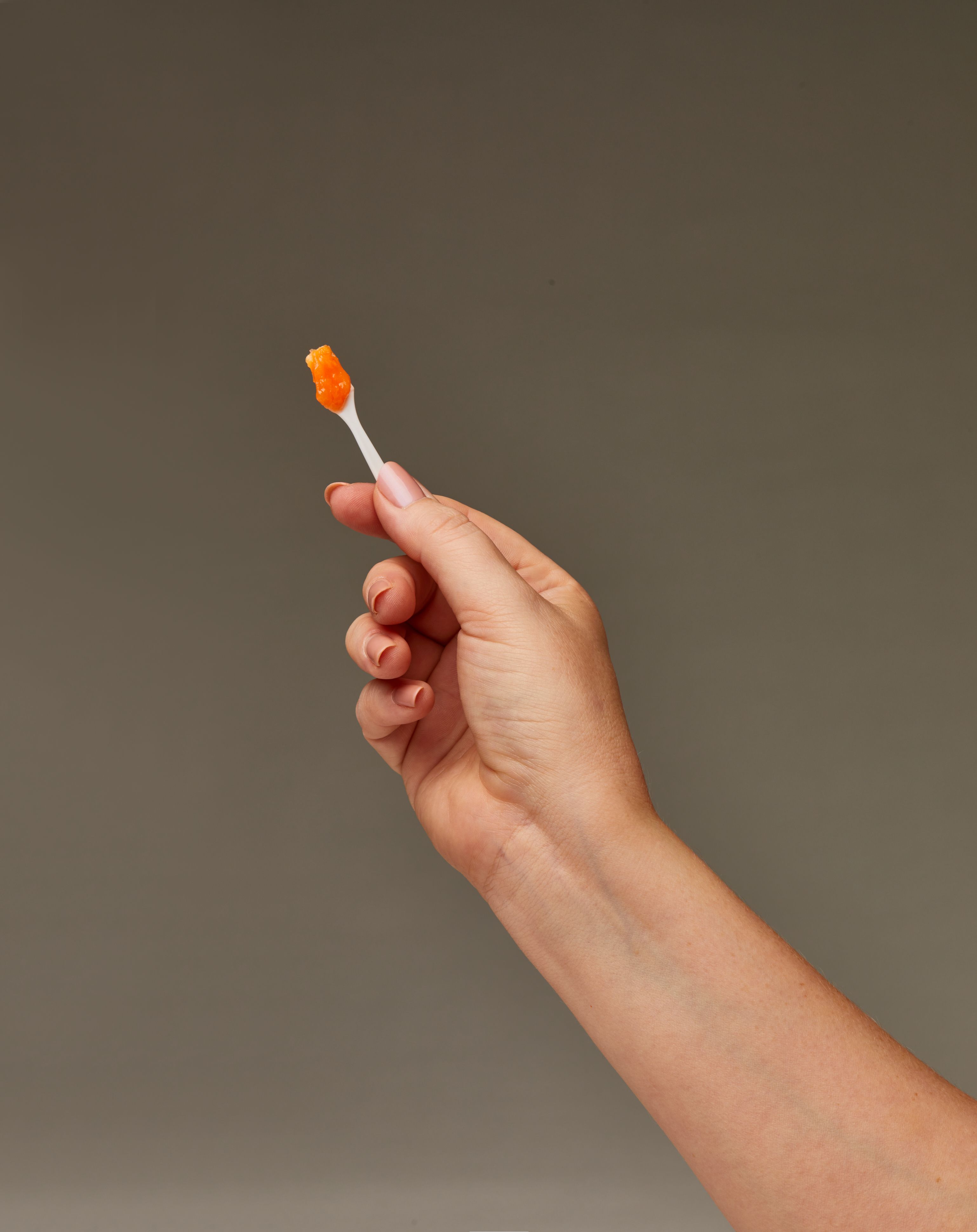 a person is holding a toothbrush with orange toothpaste on it .