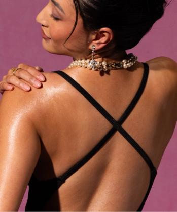 a woman in a gold dress is applying sunscreen to her shoulder