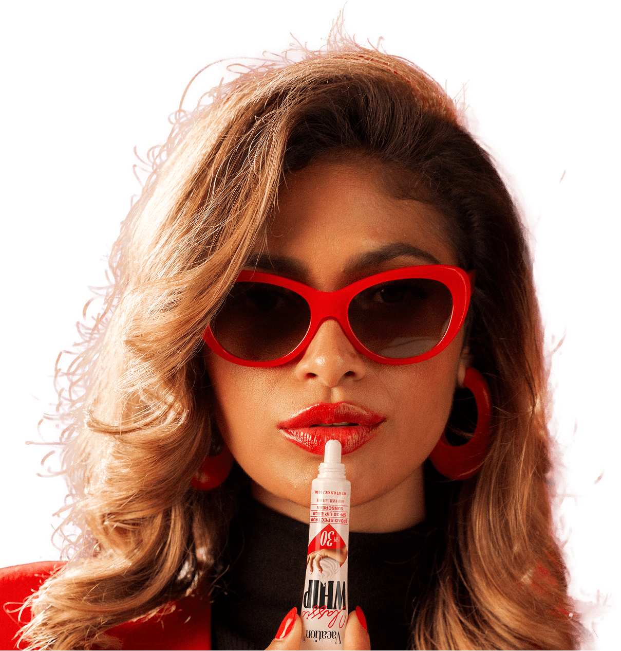A woman with wavy blonde hair, wearing red sunglasses and lipstick, holds a "Classic Whip SPF 30" lip balm tube.