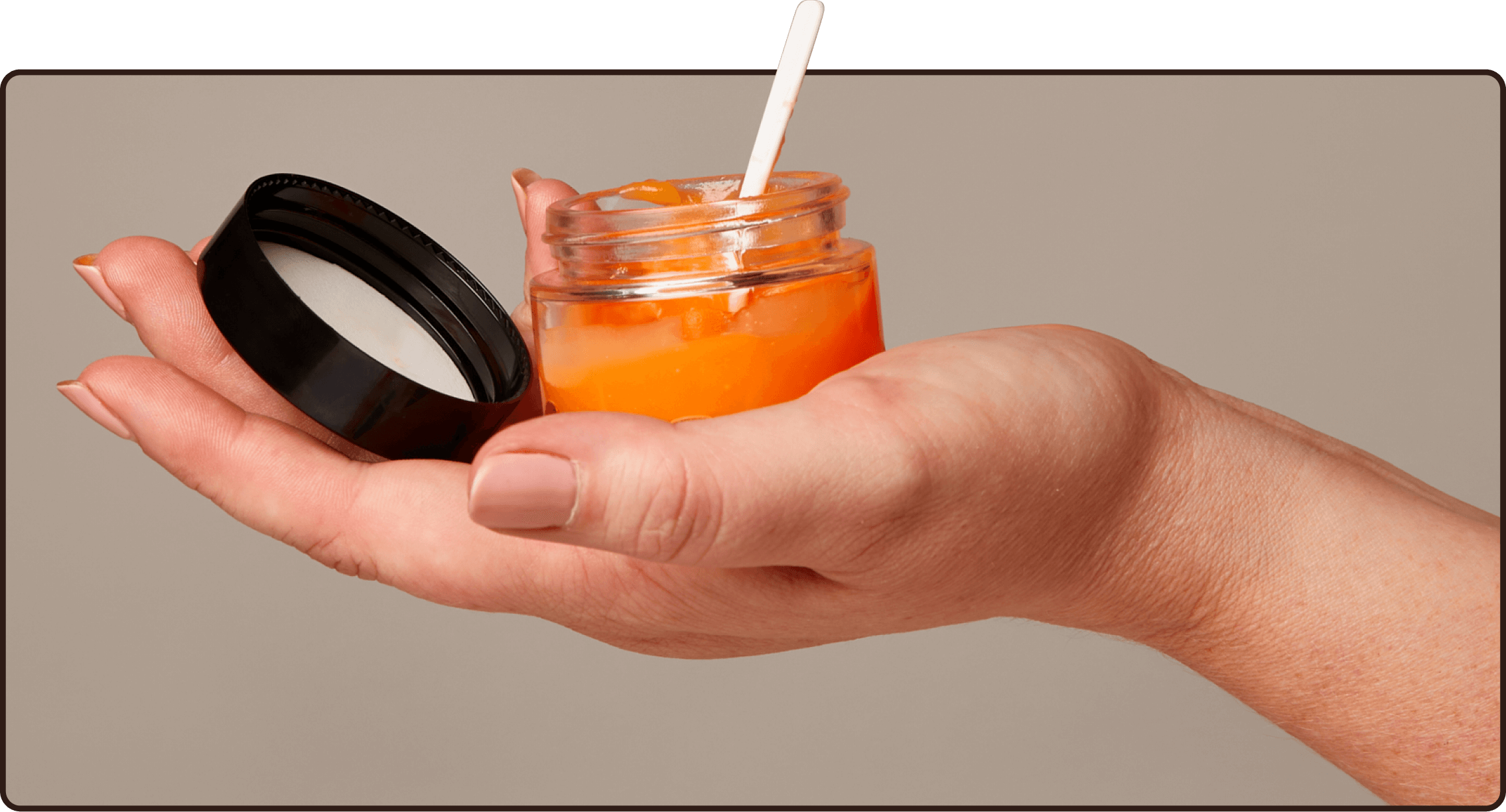 a woman holds a jar of orange liquid in her hand