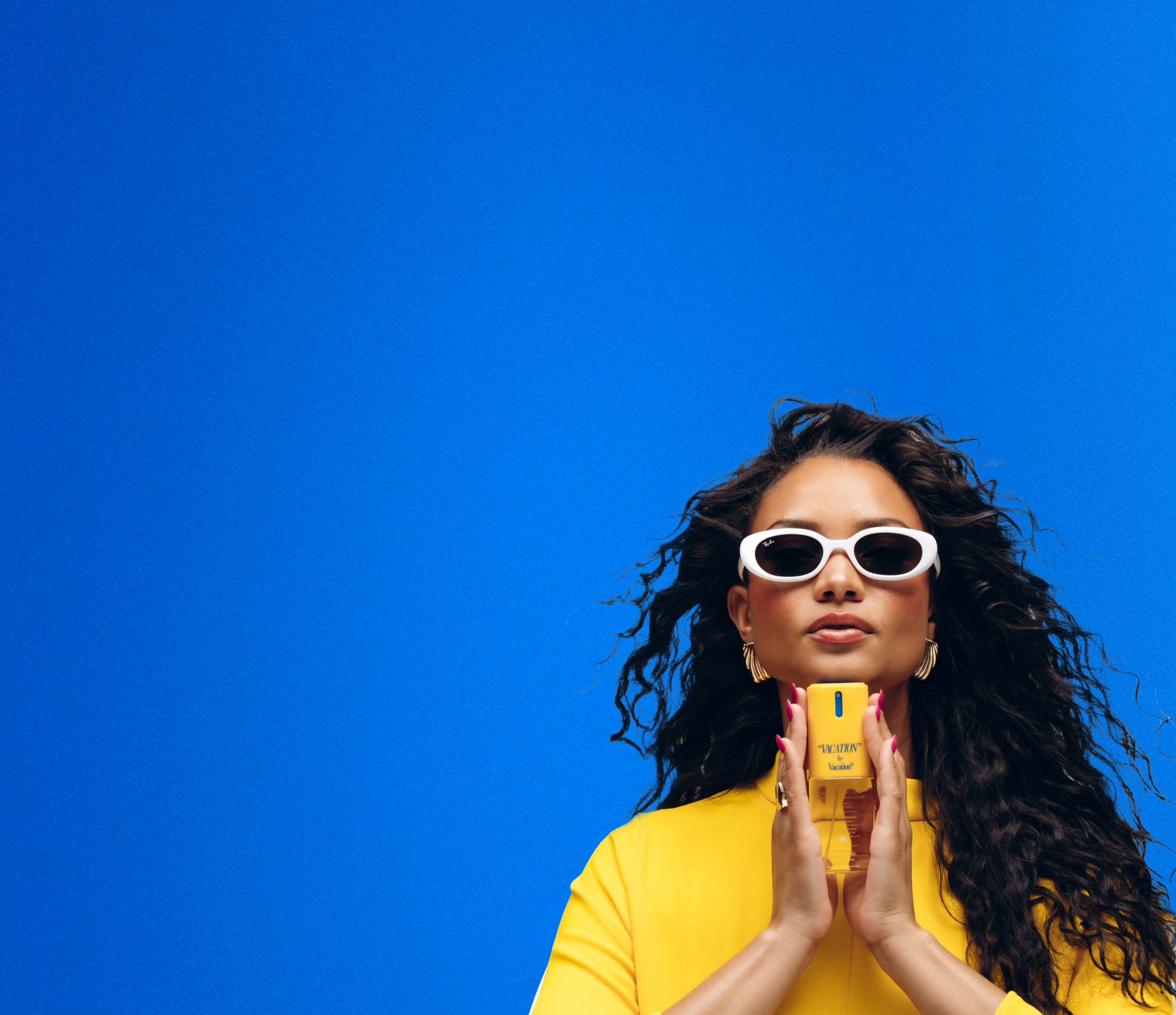 a woman in a yellow dress holding "VACATION" Body Mist