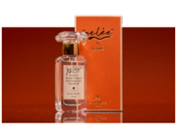 A clear glass perfume bottle with a decorative stopper stands next to an orange box.