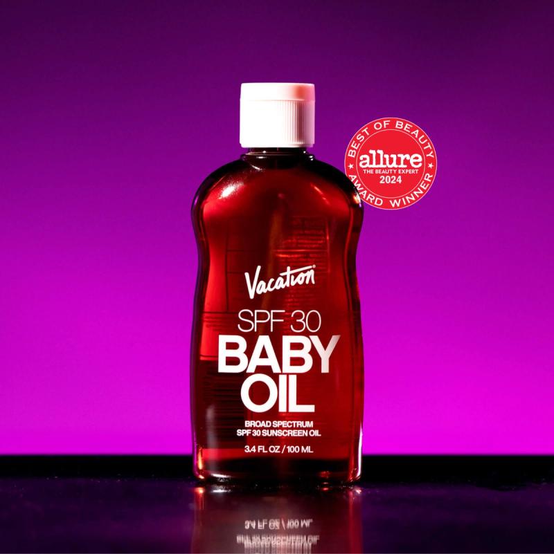 Reddish-brown bottle of Vacation SPF 30 Baby Oil sunscreen with a white cap and an Allure Best of Beauty 2022 award seal on a purple background.