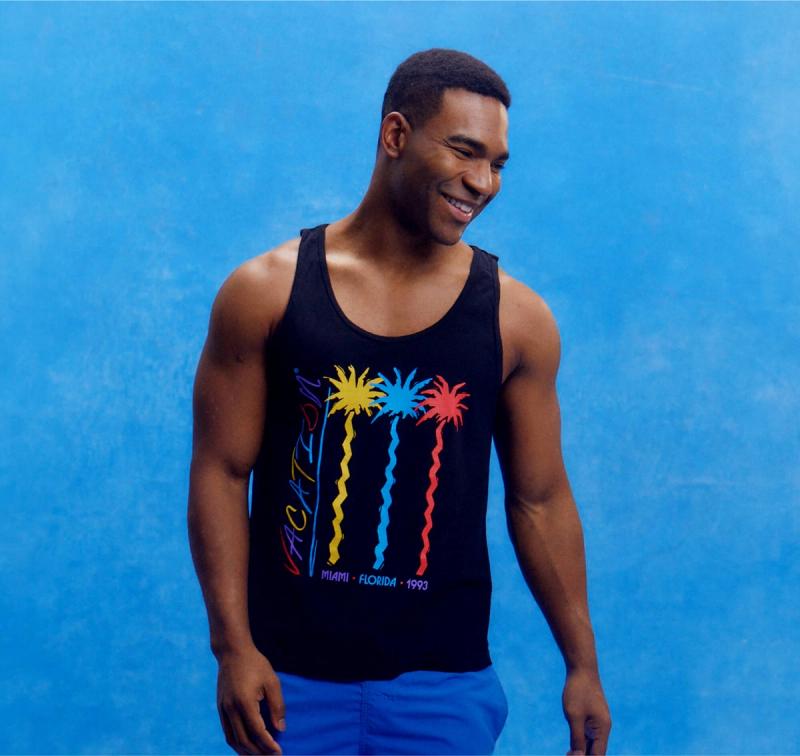 a man wearing a black Vacation® Jazz Palms tank on a blue background