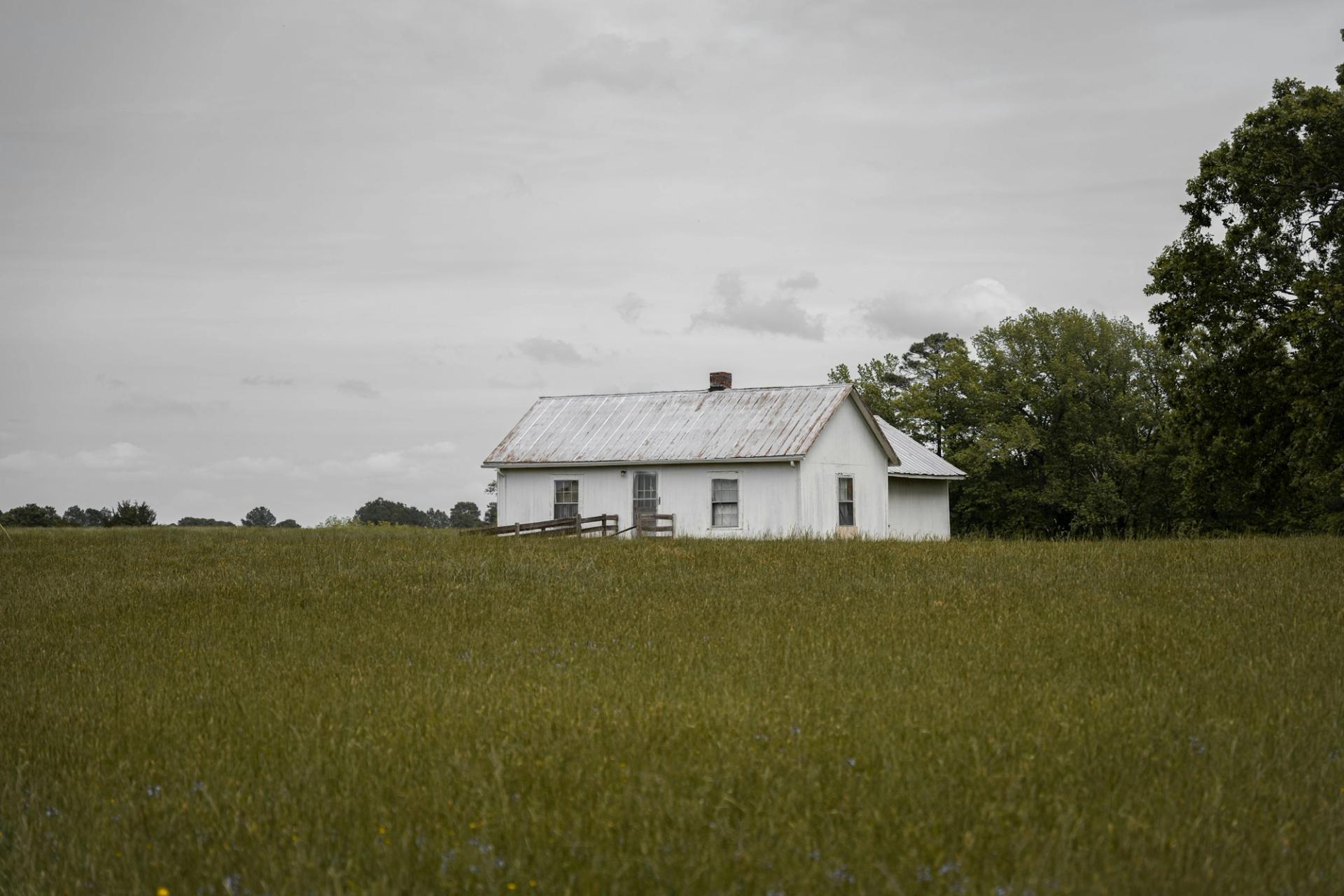 a white house in a field with trees in the background
