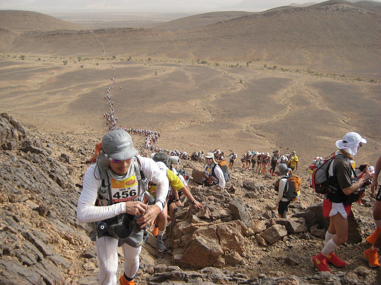 Đoàn vận động viên Marathon des Sables vác balo vượt dốc đá giữa sa mạc Sahara