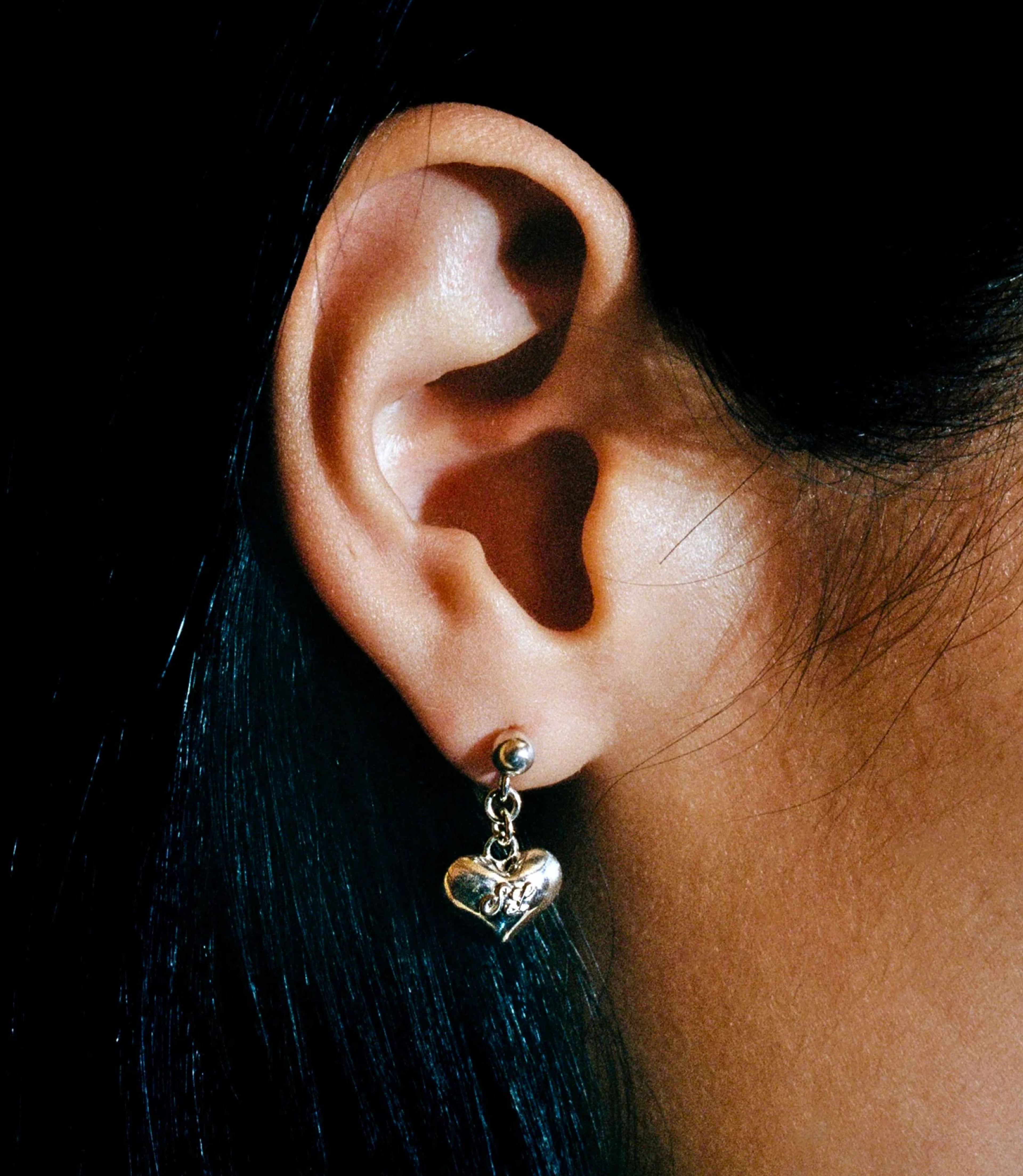 Sandy Liang silver heart earring with script "SL" acronym. Copyright Cotton Design, Talia Cotton