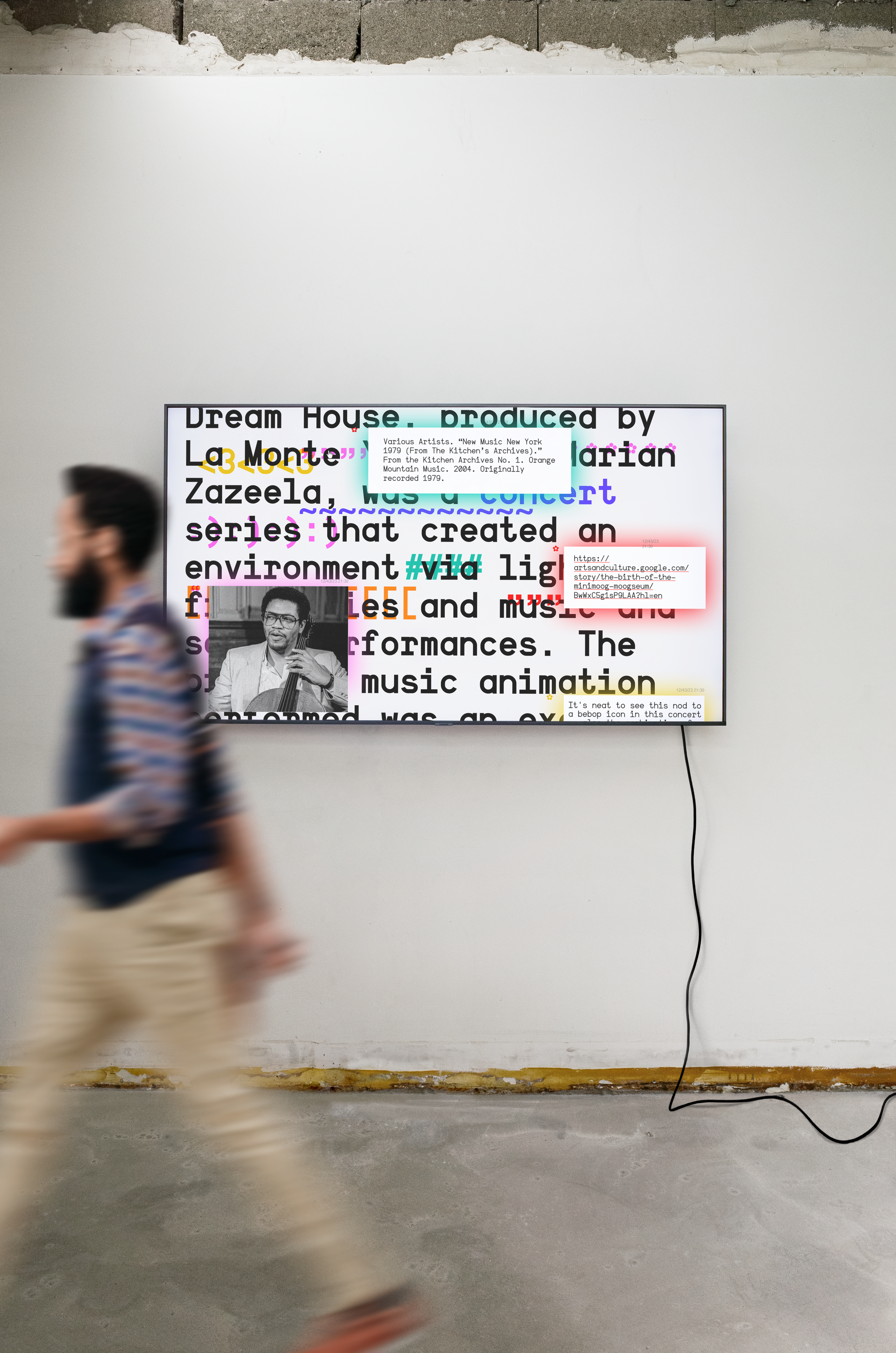 Photo view of words changing into different colors on a monitor with person walking by. Copyright Cotton Design, Talia Cotton